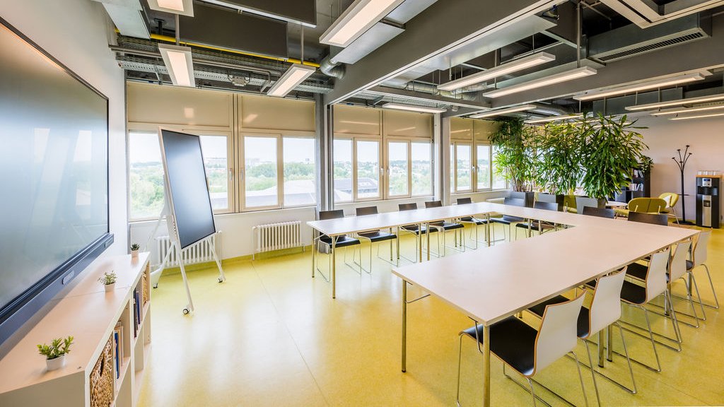 Salle de conf&eacute;rence du BLSI am&eacute;nag&eacute;e en U, pouvant accueillir jusqu&rsquo;&agrave; 35 personnes, avec un &eacute;cran interactif de 86 pouces, un tableau num&eacute;rique de 55 pouces et un espace d&eacute;tente au fond de la salle