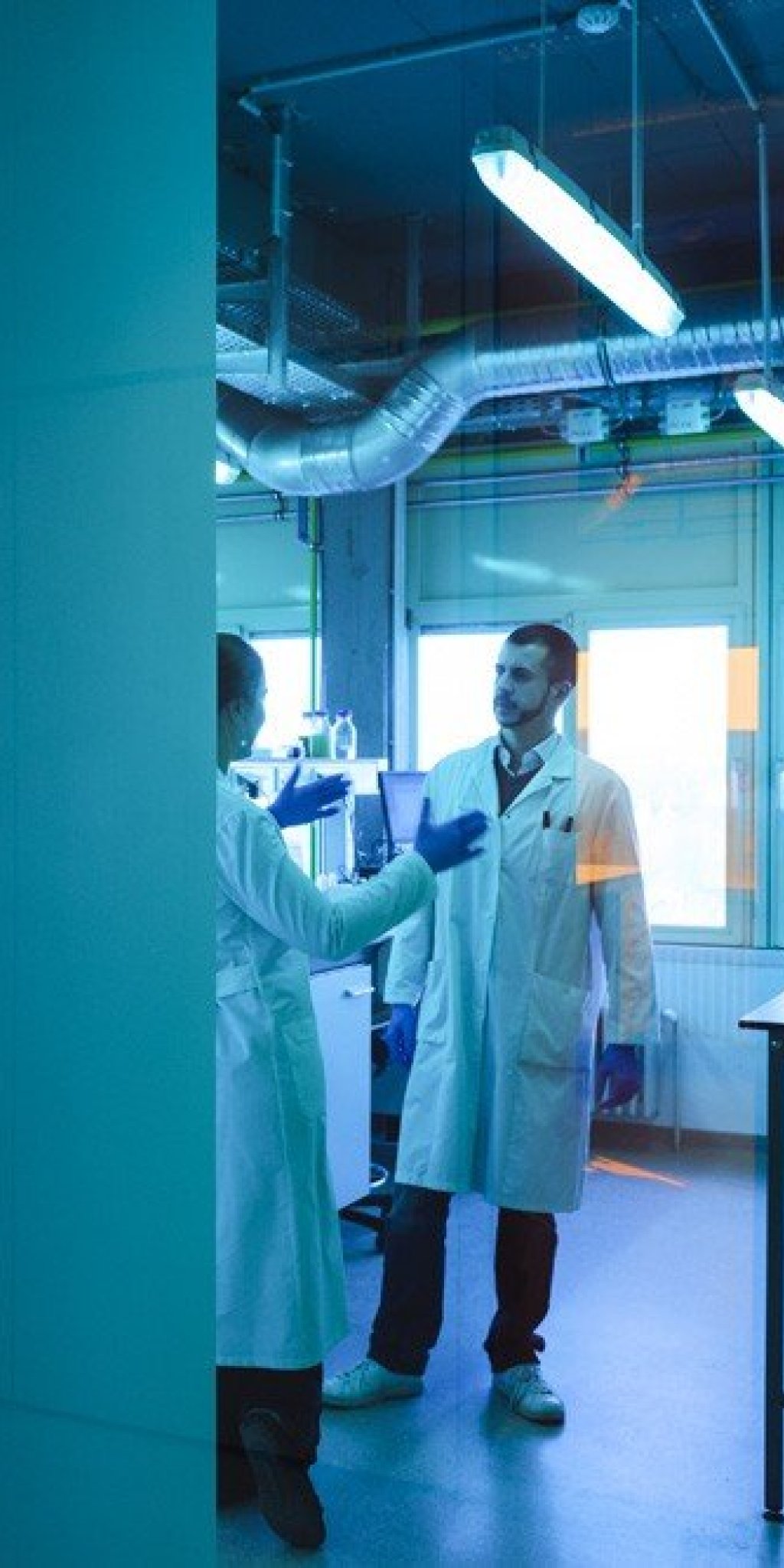 Deux laborantins en blouse &eacute;changent dans un laboratoire BSL1 au BLSI &agrave; Bruxelles