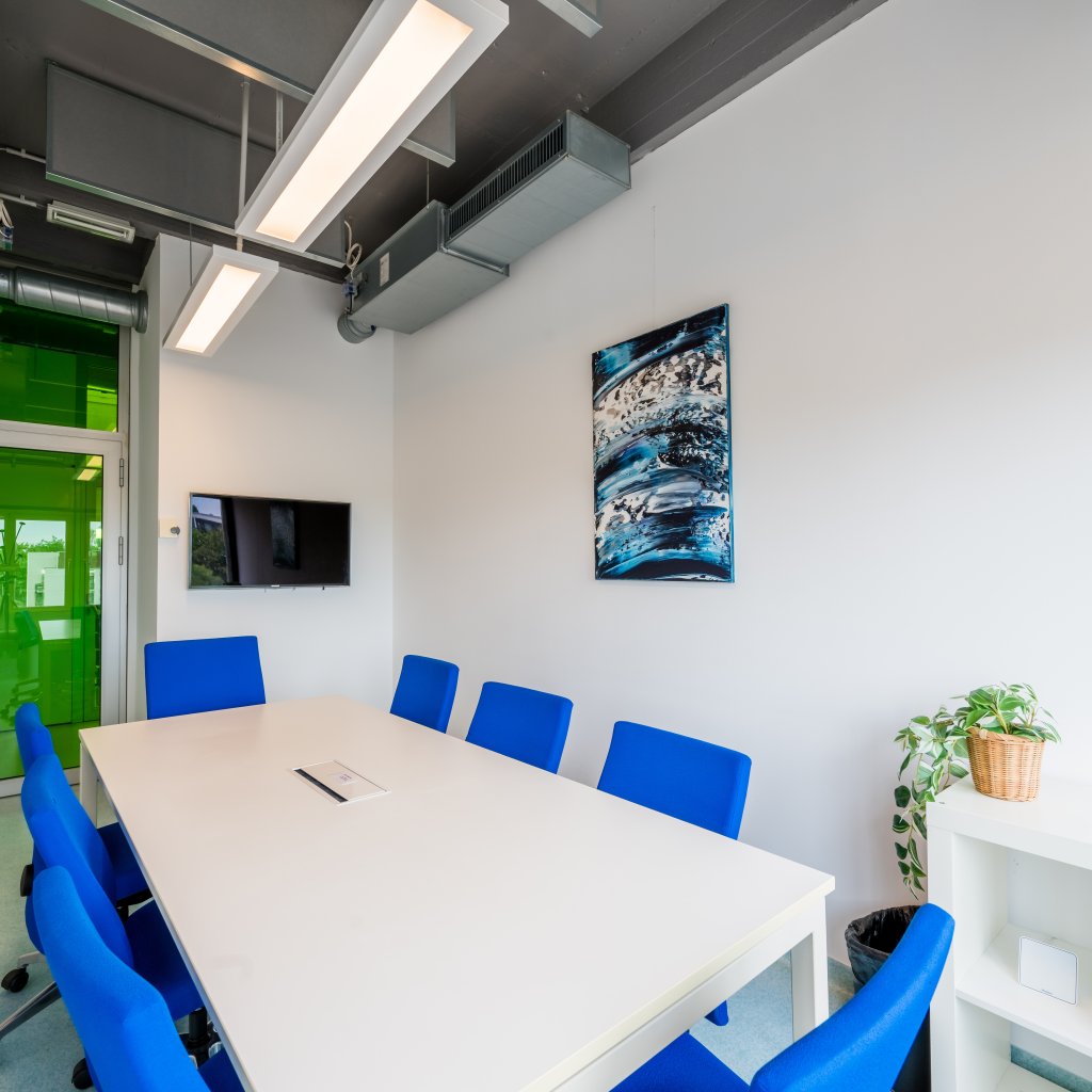 Salle de r&eacute;union du BLSI &agrave; Bruxelles pouvant accueillir jusqu&rsquo;&agrave; huit personnes autour d&rsquo;une grande table, &eacute;quip&eacute;e d&rsquo;un grand &eacute;cran LED mural